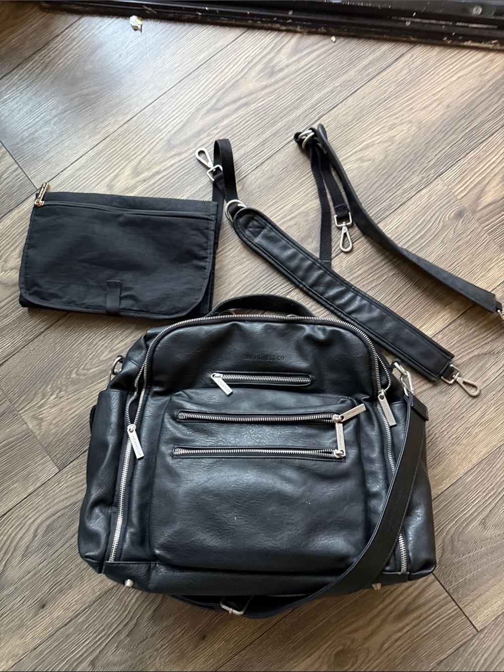 The Honest Company Black Vegan Leather Diaper Bag backpack model cross country